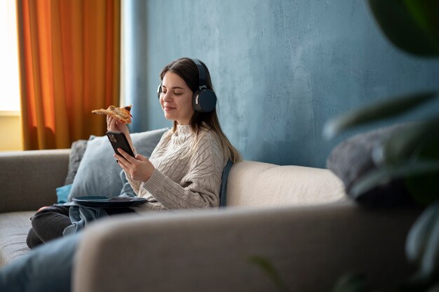 Mujer joven comiendo pizza y escuchando música