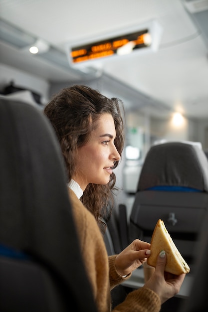 Mujer joven comiendo un sándwich mientras viaja en tren