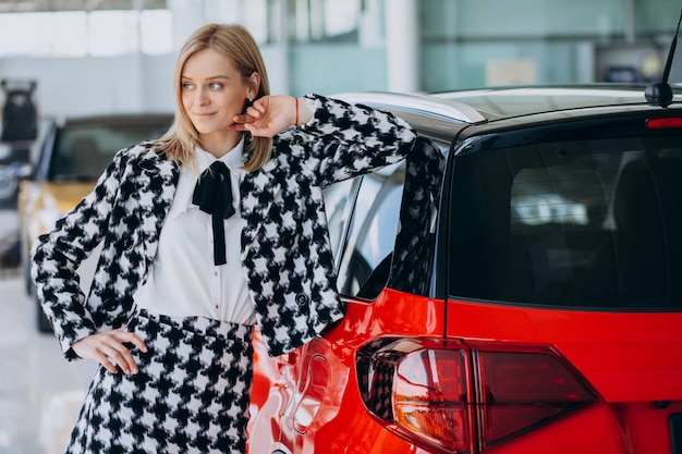 Mujer joven comprando un automóvil en una sala de exposición de automóviles