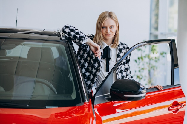 Foto gratuita mujer joven comprando un automóvil en una sala de exposición de automóviles