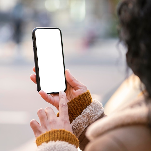 Mujer joven comprobando un smartphone de pantalla vacía