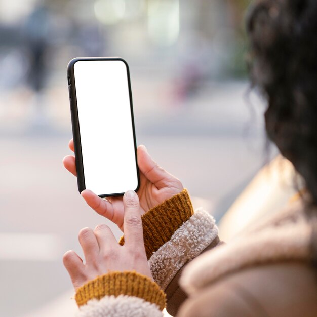 Mujer joven comprobando un smartphone de pantalla vacía