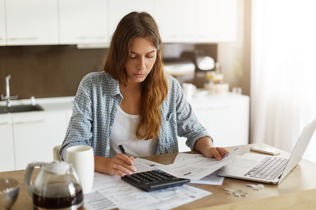 Mujer joven comprobando su presupuesto y haciendo impuestos