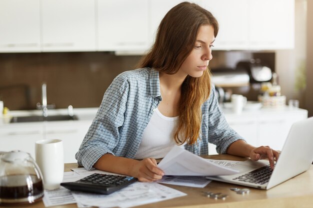 Mujer joven comprobando su presupuesto y haciendo impuestos