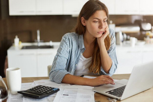 Mujer joven comprobando su presupuesto y haciendo impuestos