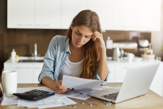 Mujer joven comprobando su presupuesto y haciendo impuestos