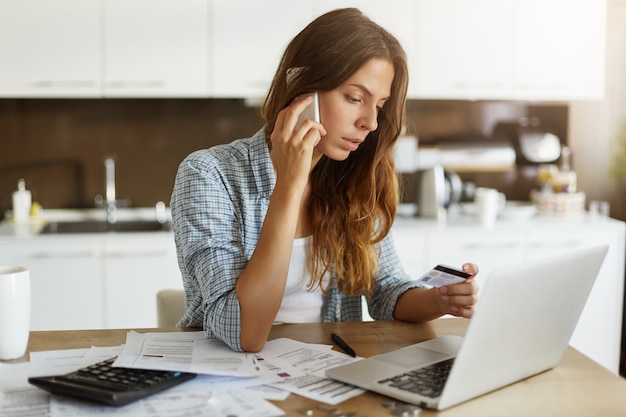 Mujer joven comprobando su presupuesto y haciendo impuestos