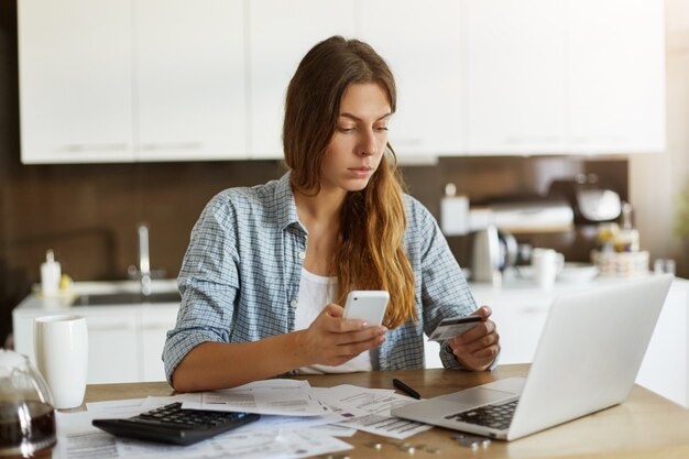 Mujer joven comprobando su presupuesto y haciendo impuestos