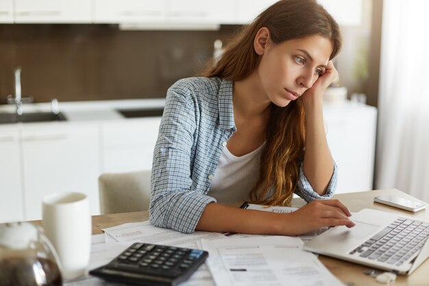 Mujer joven comprobando su presupuesto y haciendo impuestos