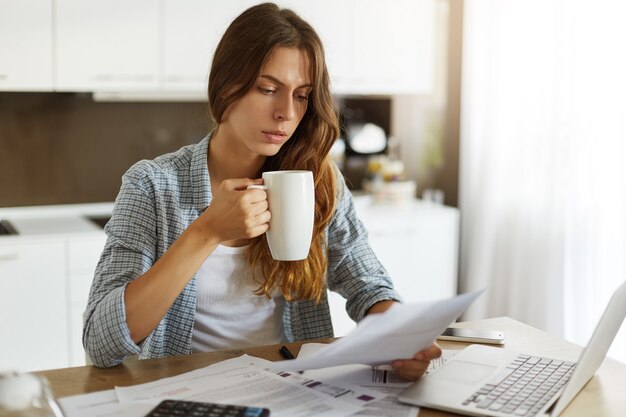 Mujer joven comprobando su presupuesto y haciendo impuestos