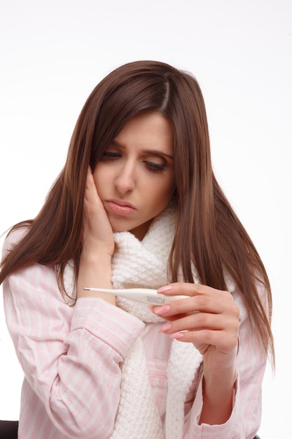 Mujer joven comprobando su temperatura con un termómetro