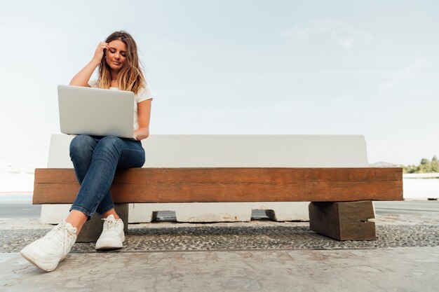 Mujer joven con una computadora portátil en un banco