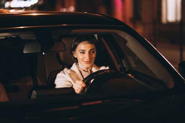 Mujer joven, conducción, en coche, por la noche
