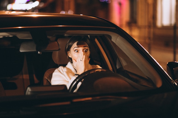 Mujer joven, conducción, en coche, por la noche