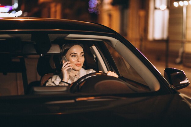 Mujer joven, conducción, en coche, por la noche