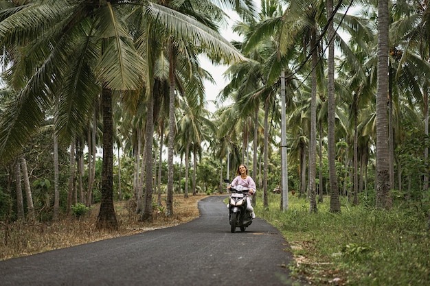 mujer joven conduciendo un ciclomotor vida tropical