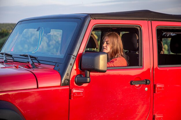 Una mujer joven conduciendo un todoterreno en el campo.