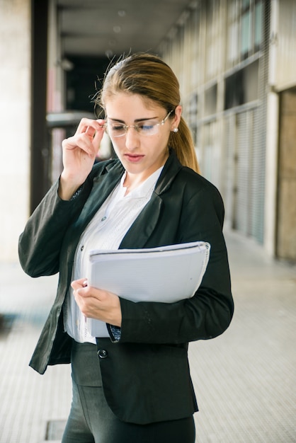 Mujer joven confiada que lleva a cabo el documento disponible