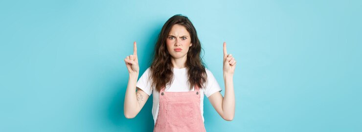 Foto gratuito mujer joven confundida y conmocionada frunciendo el ceño mirando a la cámara disgustada exige respuestas apuntando finge