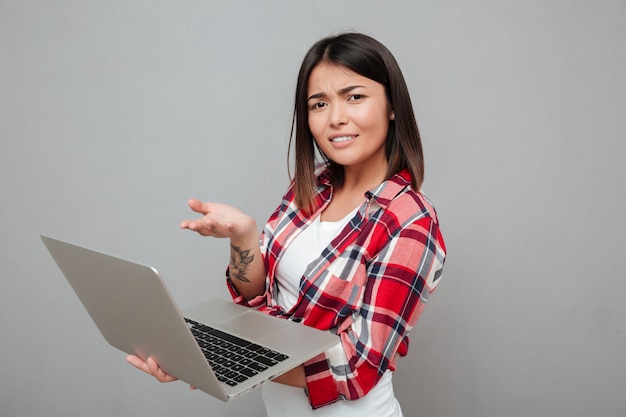 Mujer joven confundida con ordenador portátil.