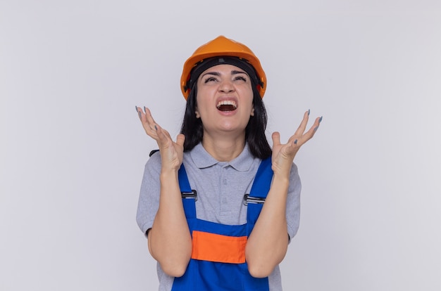 Mujer joven constructor en uniforme de construcción y casco de seguridad gritando