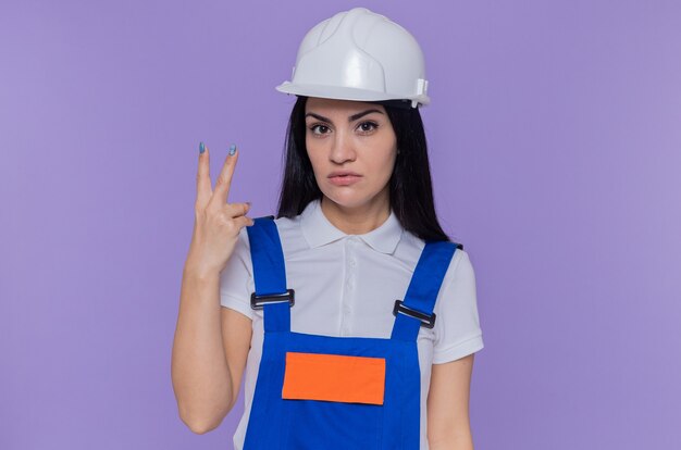 Mujer joven constructor en uniforme de construcción y casco de seguridad