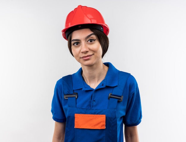 Mujer joven constructora complacida en uniforme aislado en la pared blanca