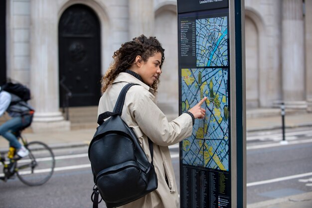 Mujer joven consultando un mapa de la estación en la ciudad