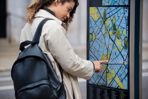 Mujer joven consultando un mapa de la estación en la ciudad