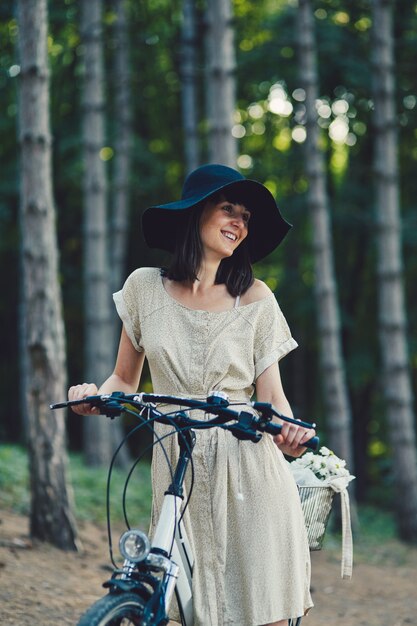 Mujer joven contra el fondo de la naturaleza con bicicleta