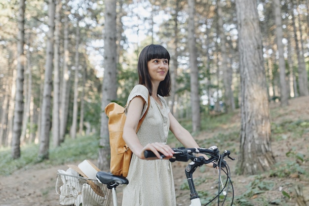 Mujer joven contra el fondo de la naturaleza con bicicleta