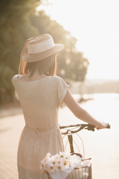 Mujer joven contra el fondo de la naturaleza con bicicleta