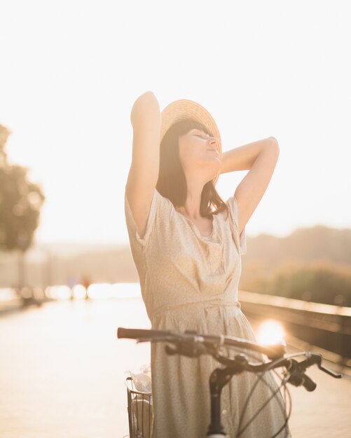 Mujer joven contra el fondo de la naturaleza con bicicleta