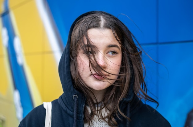 Una mujer joven contra un graffiti urbano de pared amarilloazul