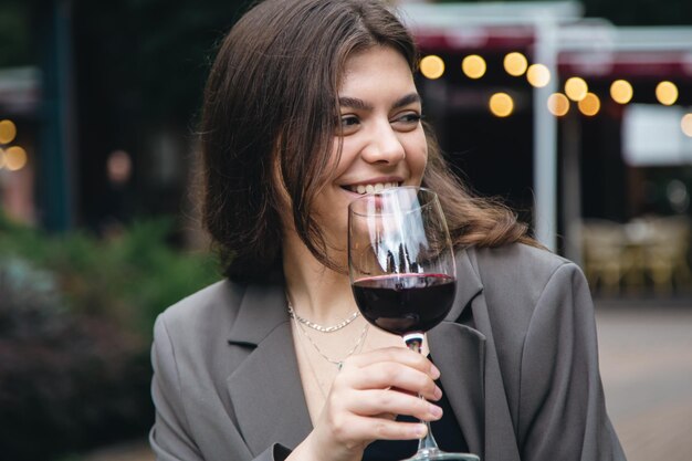 Una mujer joven con una copa de vino afuera cerca de un restaurante