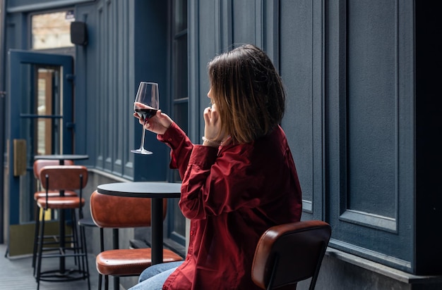 Una mujer joven con una copa de vino en la terraza de un restaurante