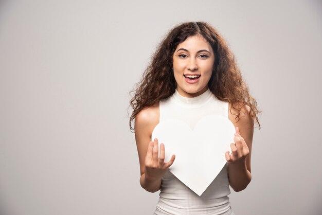 Mujer joven con corazón de papel hecho a mano blanco. Foto de alta calidad