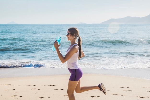 Foto gratuita mujer joven corriendo y bebiendo