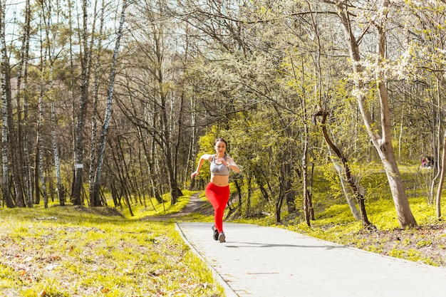 Mujer joven corriendo a través de los árboles