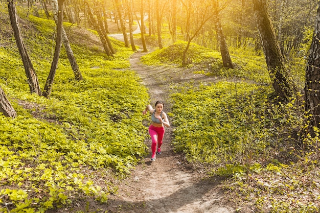 Mujer joven corriendo a través de los árboles