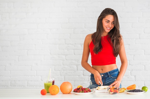 Foto gratuita mujer joven cortando una rodaja de plátano a bordo