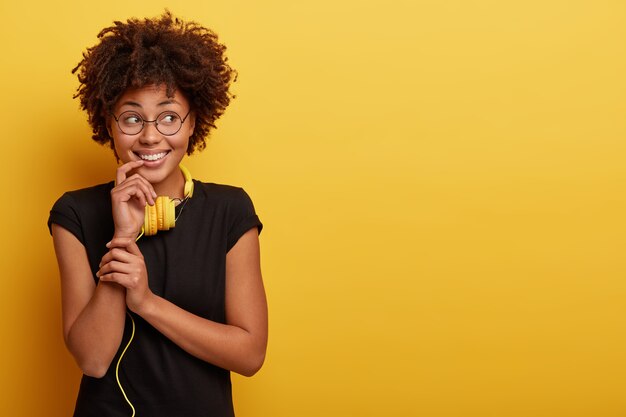 Mujer joven con corte de pelo afro y auriculares amarillos