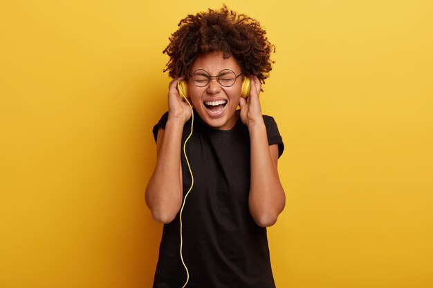 Mujer joven con corte de pelo afro y auriculares amarillos