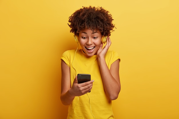 Mujer joven con corte de pelo afro y auriculares amarillos