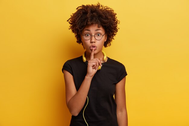 Mujer joven con corte de pelo afro con auriculares amarillos