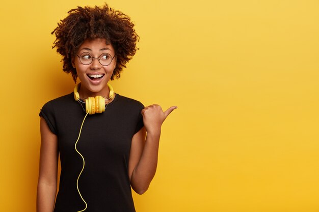 Mujer joven con corte de pelo afro con auriculares amarillos