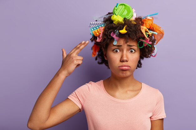 Mujer joven con corte de pelo afro y desechos plásticos en su cabello