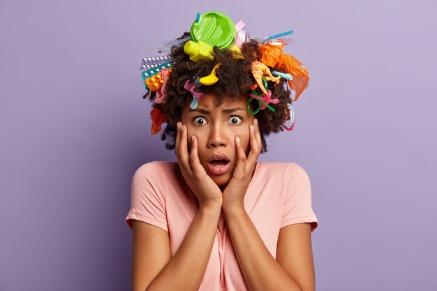 Mujer joven con corte de pelo afro y desechos plásticos en su cabello