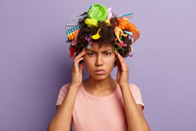 Mujer joven con corte de pelo afro y desechos plásticos en su cabello