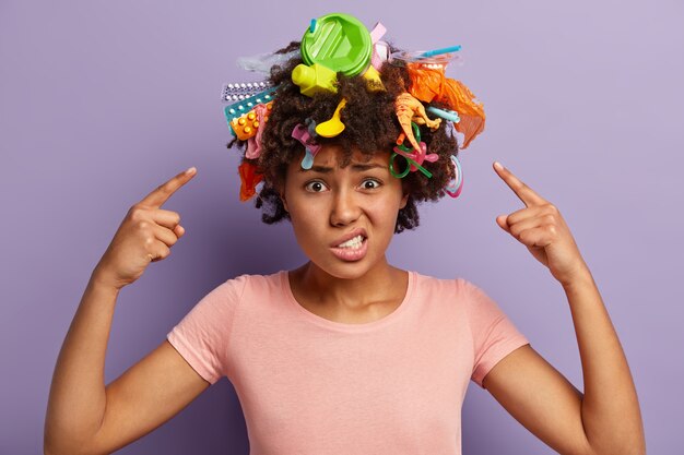 Mujer joven con corte de pelo afro y desechos plásticos en su cabello